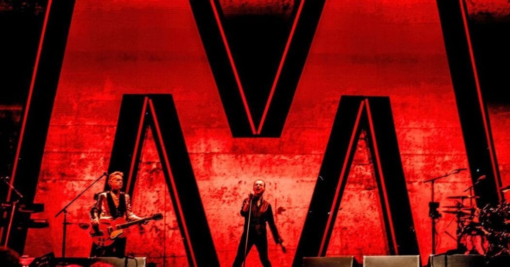 Depeche Mode en concierto con la M en rojo detrás